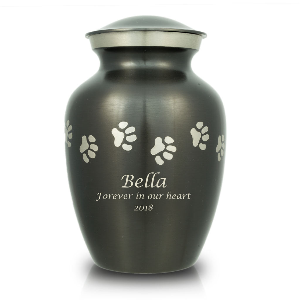 Slate grey pet urn with etched pewter paw prints walking around the urn and a sample of engraving on the front.