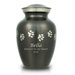 Slate grey pet urn with etched pewter paw prints walking around the urn and a sample of engraving on the front.