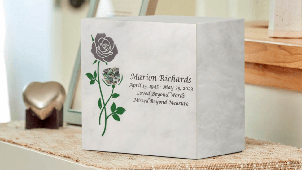 A square white memorial urn with a rose and green stem, plus custom personalized text reading Loved Beyond Words Missed Beyond Measure