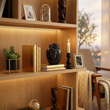 Natural extra small black marble urn with white veining in a home decor setting on a bookshelf.