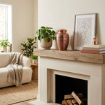 Traditional metal urn with a polished copper finish featuring an elegant etched leaf design above a fireplace.