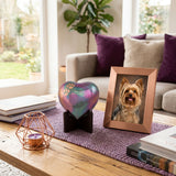 Raku heart for cremation ashes with beautiful green, pink, and purple shimmering finish with copper paw prints on a heart stand in a home decor setting on a coffee table.