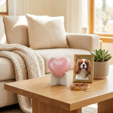 Shimmery pink brass heart dog urn featuring two silver paw prints in a home decor setting.