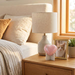 Pink heart cat urn with two silver paw prints in a home decor setting.