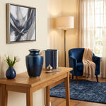 Modern metal urn in a dark blue, shimmery finish with pewter accents in a home decor setting.
