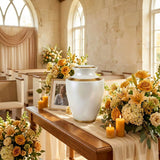 Modern metal cremation urn with a shimmery pearl finish and golden accents in a funeral service setting.