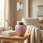 Metal cremation urn featuring a pink Asian-inspired silhouette and pewter lid in a home decor setting.