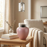 Metal cremation urn featuring a pink Asian-inspired silhouette and pewter lid in a home decor setting.