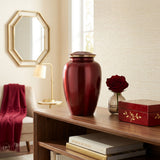 Red metal cremation urn in a traditional shape with gold accent in a home decor setting.