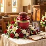 Red urn with metallic finish featuring a gold band in a funeral service setting.