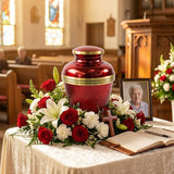 Red urn with metallic finish featuring a gold band in a funeral service setting.