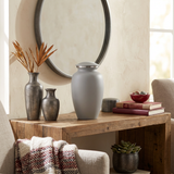 Elegant metal greyish white cremation urn in a home decor setting on a table