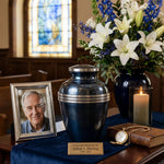 Metal metallic blue banded cremation urn in large in a funeral service setting.