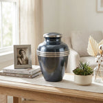 Metal metallic blue banded cremation urn in large un a cozy home decor setting on a table.