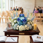 Blue floral cloisonne urn with gold accents in a funeral service setting.