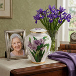 Vibrant white cloisonne cremation urn featuring purple irises with gold accents in a home decor setting.