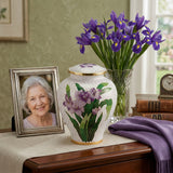 Vibrant white cloisonne cremation urn featuring purple irises with gold accents in a home decor setting.