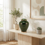 Green cloisonne urn featuring a delicate floral motif and gold accents in a home decor setting.