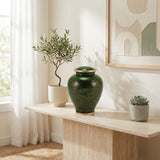 Green cloisonne urn featuring a delicate floral motif and gold accents in a home decor setting.