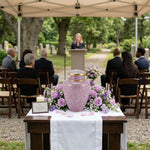 Pink cloisonne cremation urn featuring a floral motif with gold accents in an outdoor celebration of life setting.