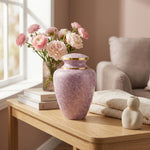 Pink cloisonne cremation urn featuring a floral motif with gold accents in a bright, modern home decor setting.