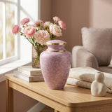 Pink cloisonne cremation urn featuring a floral motif with gold accents in a bright, modern home decor setting.