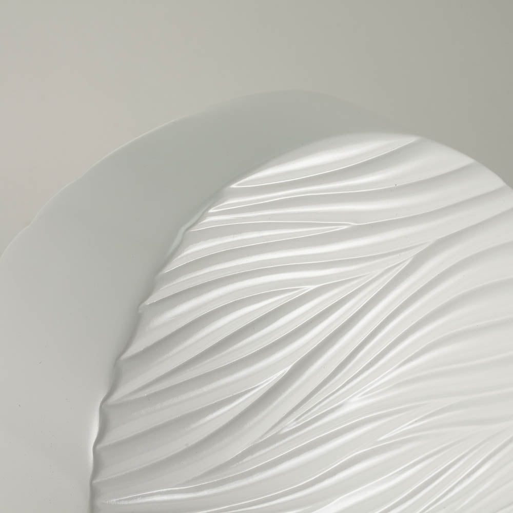 Round white ceramic cremation urn with soft, polished wave pattern detail image.