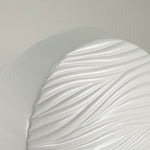 Round white ceramic cremation urn with soft, polished wave pattern detail image.