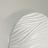 Round white ceramic cremation urn with soft, polished wave pattern detail image.