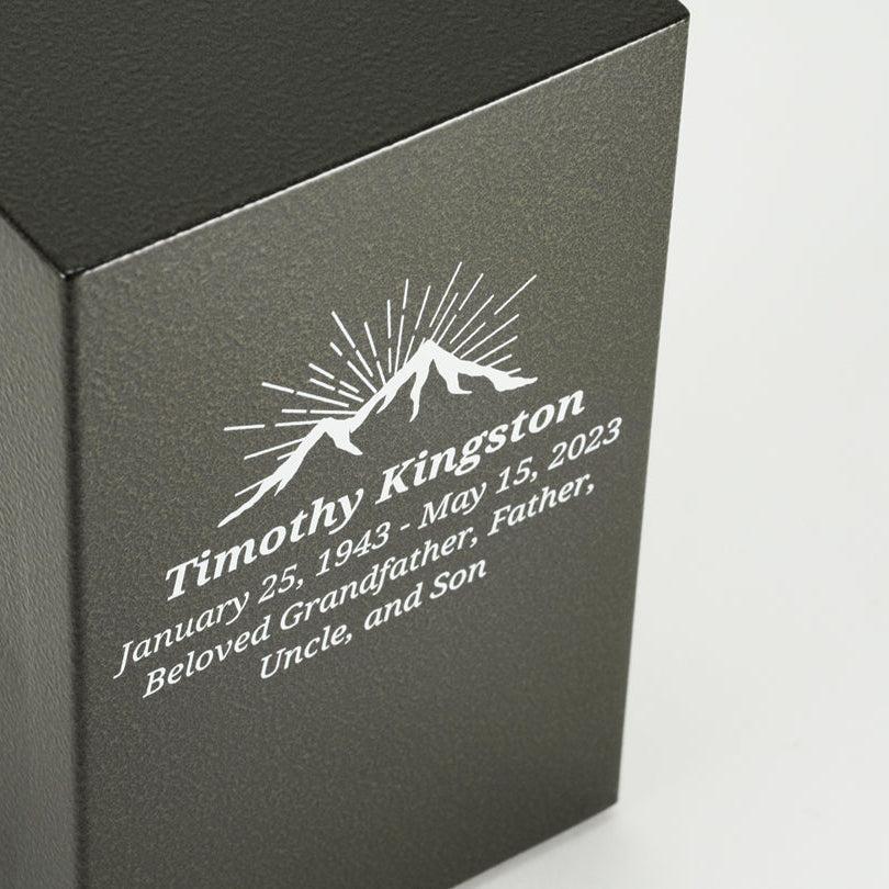 A bold steel urn box with antique bronze powder coat textured finish close up image of personalization.