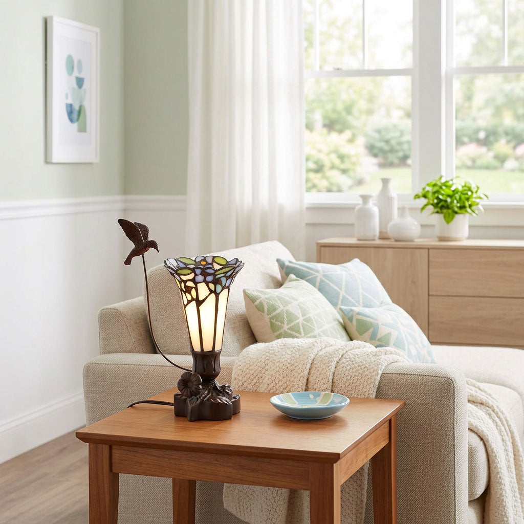 Tiffany styled cremation keepsake lamp that resembles a hummingbird feeding from a flower, with white and blue tones in a home decor setting.