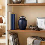 Two-tone dark blue aluminum metal cremation urn in medium in a home decor setting.
