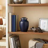 Two-tone dark blue aluminum metal cremation urn in medium in a home decor setting.
