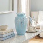 Light blue metal urn with hand etching in an intricate design in a home decor setting.