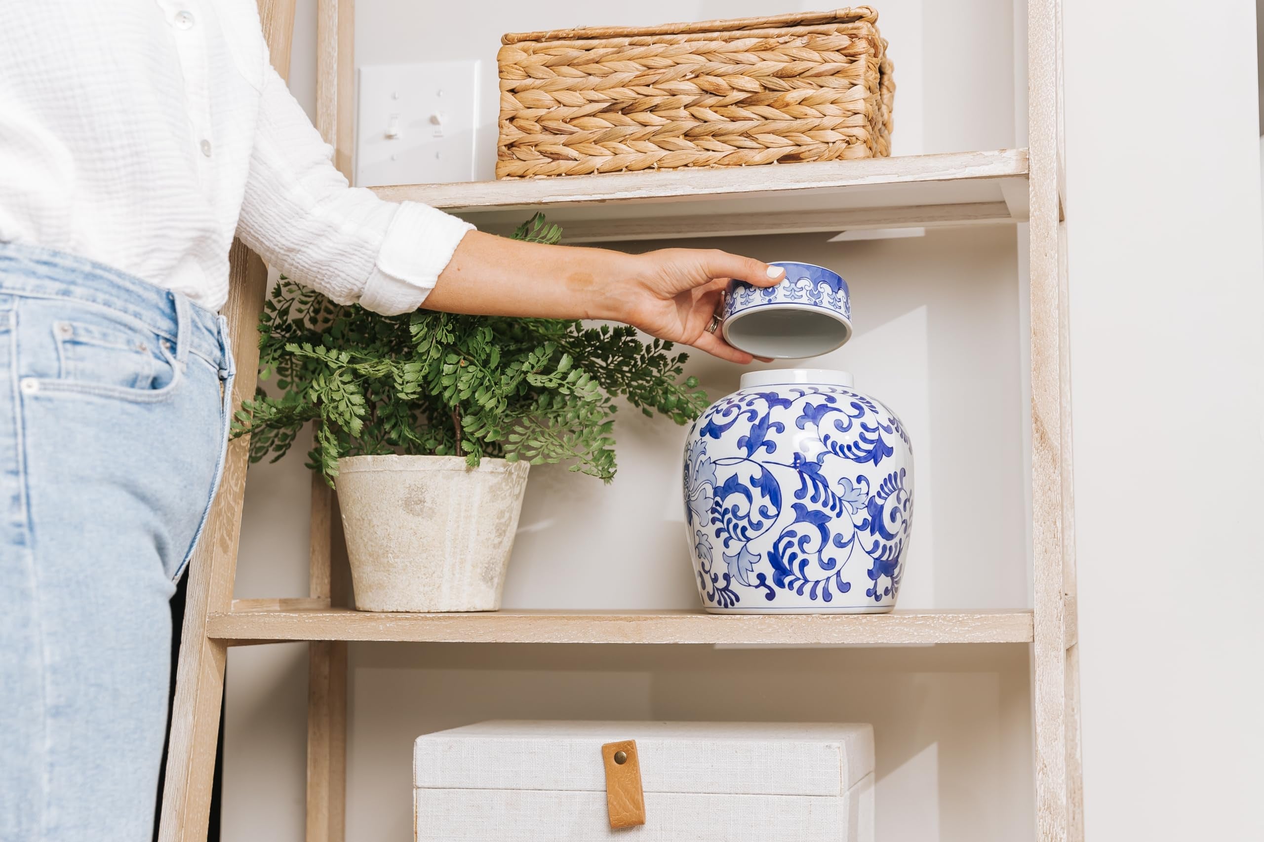 Hand holding blue and white ceramic cremation urn with ornate swirl pattern