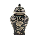 A black ceramic lidded urn in ginger jar style with a cream floral chinoiserie pattern, photographed against a solid white background.