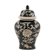 A black ceramic lidded urn in ginger jar style with a cream floral chinoiserie pattern, photographed against a solid white background.