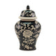 A black ceramic lidded urn in ginger jar style with a cream floral chinoiserie pattern, photographed against a solid white background.