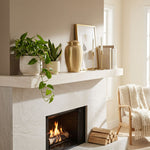 Golden metal cremation urn above a fireplace.