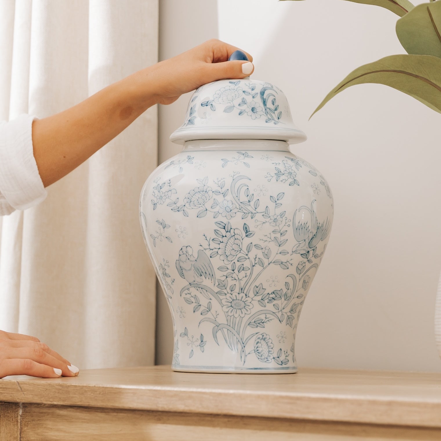 Large blue ceramic cremation urn for ashes with blue flowers sitting on console table, for perfect memorials to honor your loved one