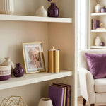 Metal cremation keepsake containing a  tealight candle holder in a gold finish in a home decor setting.