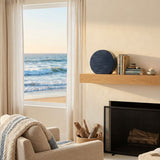 Modern blue ceramic urn featuring a sculptural tranquil wave design above a fireplace.