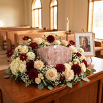 Pink, burgundy, and white natural marble box cremation urn in a funeral service setting.