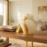 Extra small natural marble cremation urn in cream and green finish with brown veining in a home decor setting on a bookshelf.