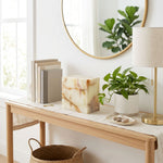 Cream and green natural marble box cremation urn in a home decor setting next to a plant.