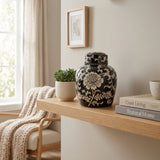 Black floral ceramic urn featuring a lotus design in a home decor setting.