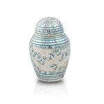 Small keepsake urn for human ashes with intricate etched pattern of doves in flight with blue paint fill.