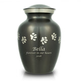 Slate grey pet urn with etched pewter paw prints walking around the urn and a sample of engraving on the front.