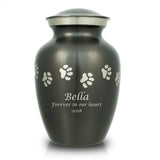 Slate grey pet urn with etched pewter paw prints walking around the urn and a sample of engraving on the front.
