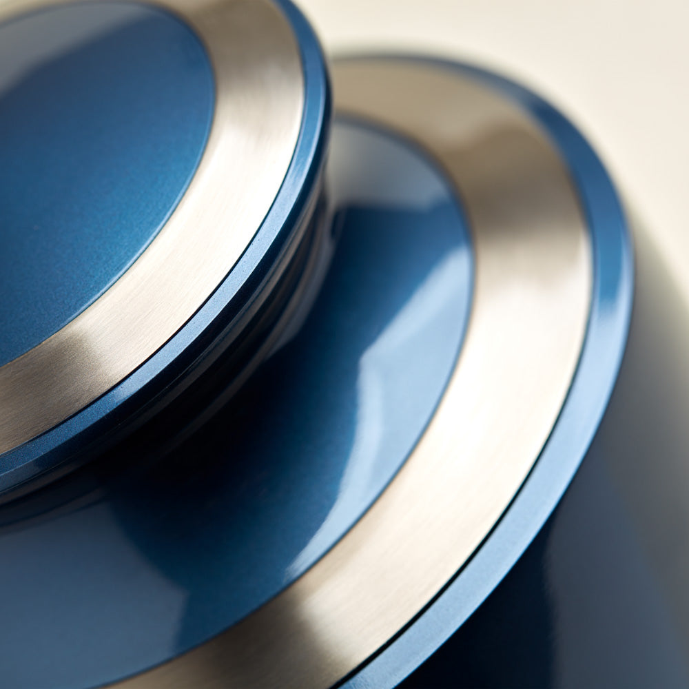 Modern metal urn in a dark blue, shimmery finish with pewter accents detail image.